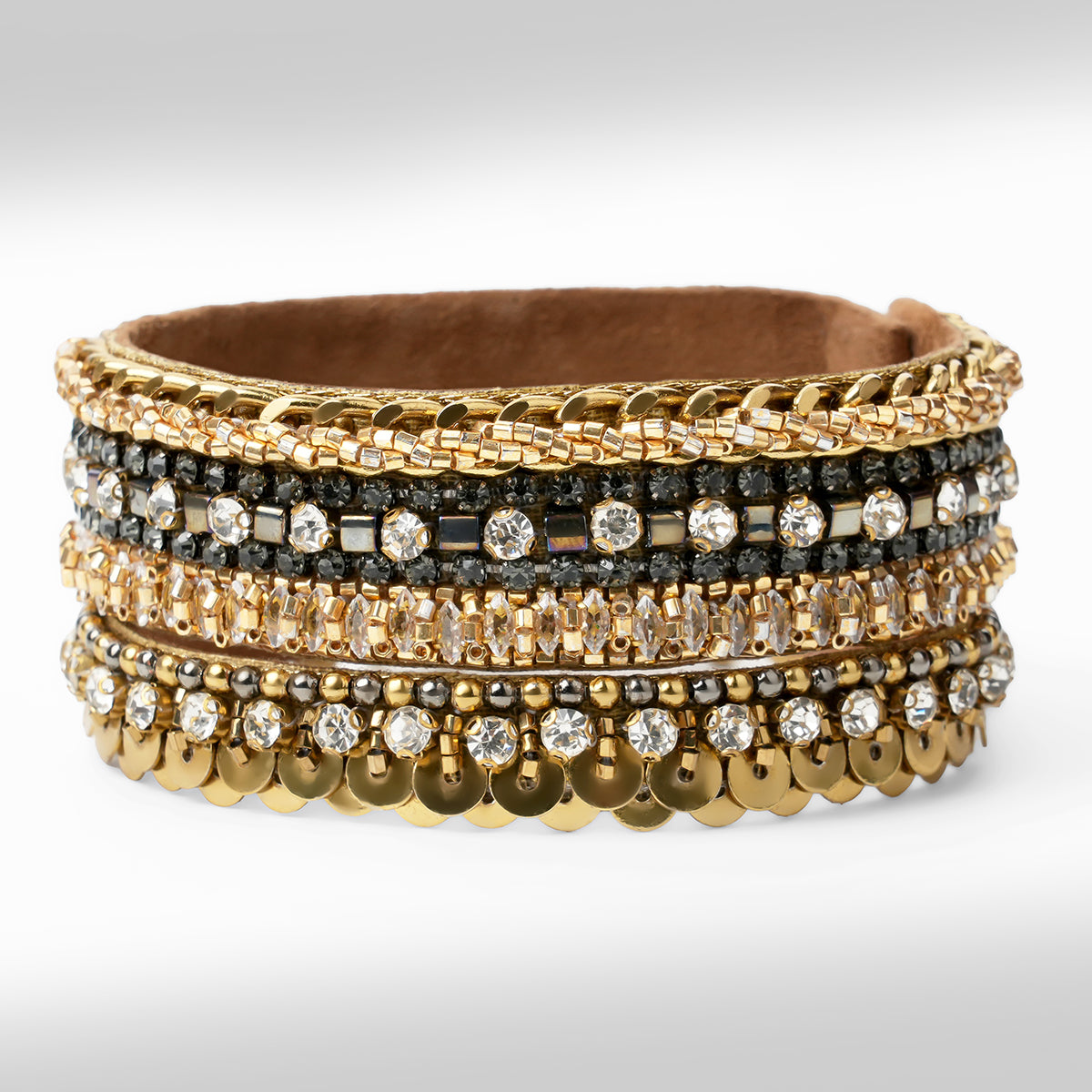 A  gold-tone bracelet with mixed crystal and bead embellishments, shown on a light gray gradient background.