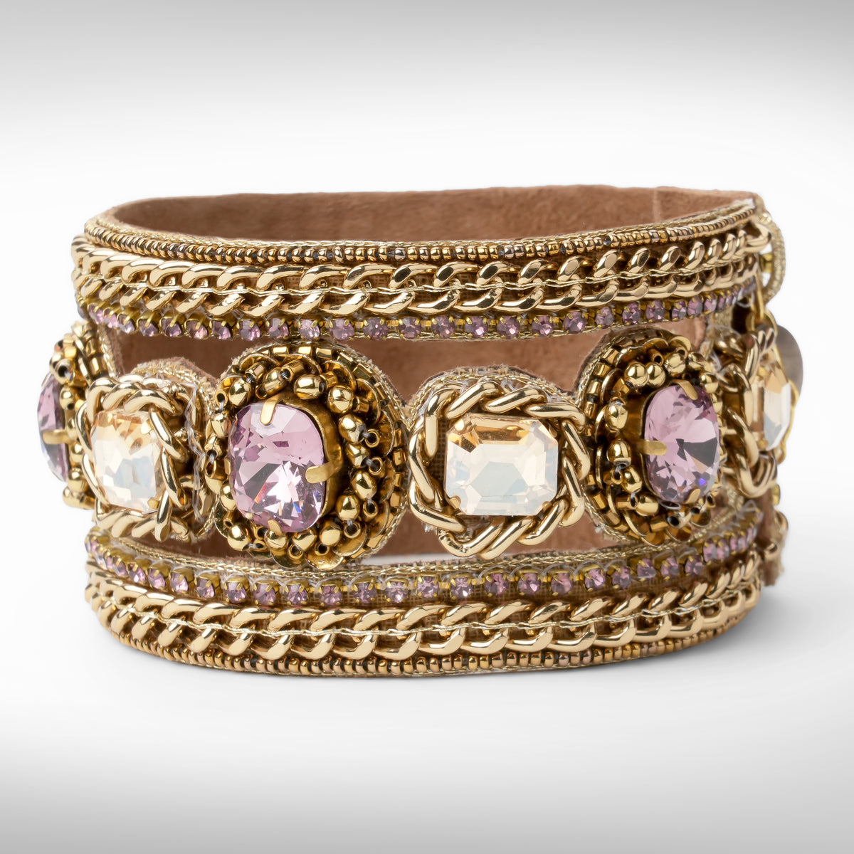 A wide gold-tone cuff bracelet featuring woven chain details, ornate floral medallions with clear and amethyst faceted crystals, and rows of small amethyst stones, shown on a light gray background.