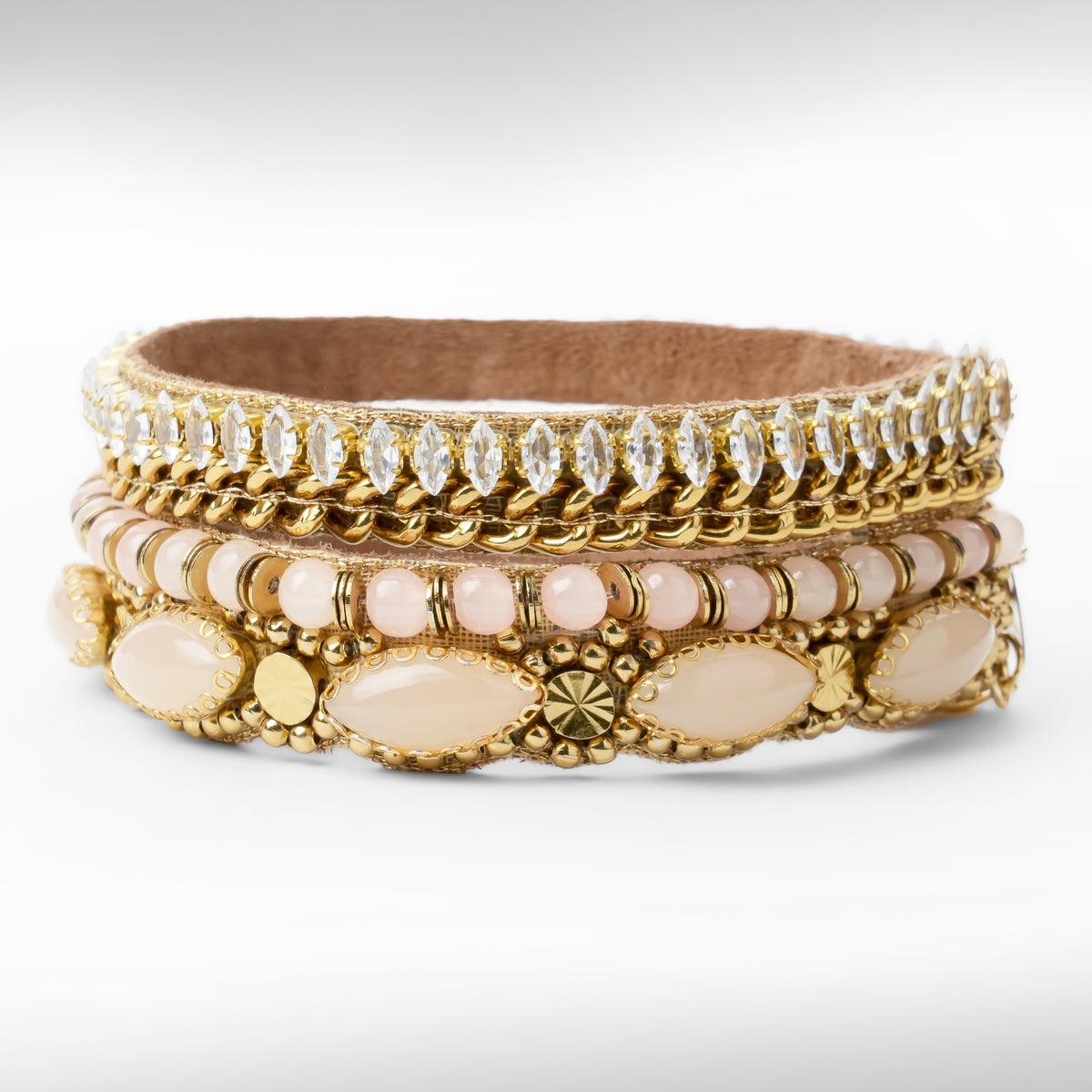 A gold-toned beaded and rhinestone bracelet with pale pink beads and oval stone accents, photographed on a clean white background.