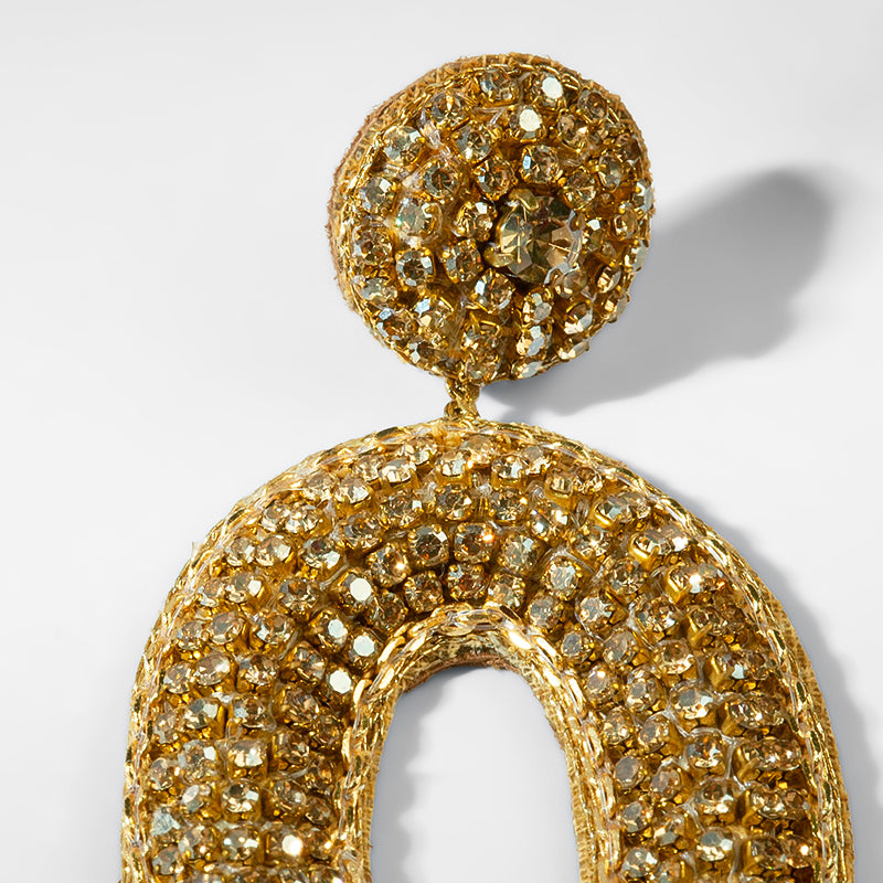Gold earring with intricate design on a light gray background