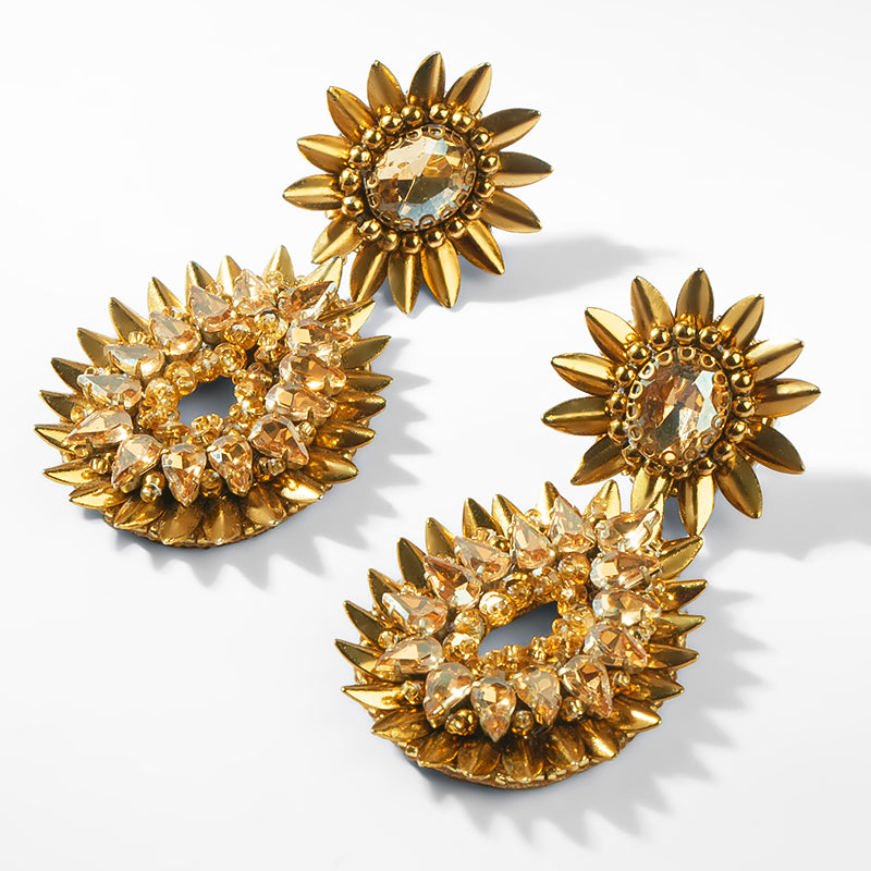 Set of gold earrings with starburst design on a white background