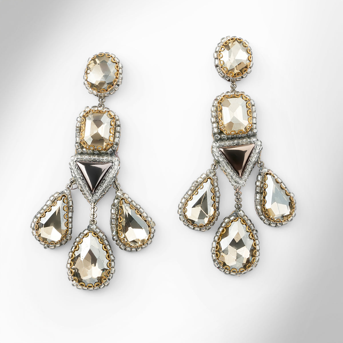 A pair of ornate silver-toned statement earrings with faceted gunmetal and silver stones, displayed on a clean light gray background.