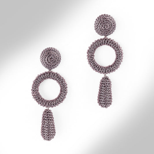 A pair of textured, multi-layered dangle earrings in a metallic finish on a light gray gradient background.