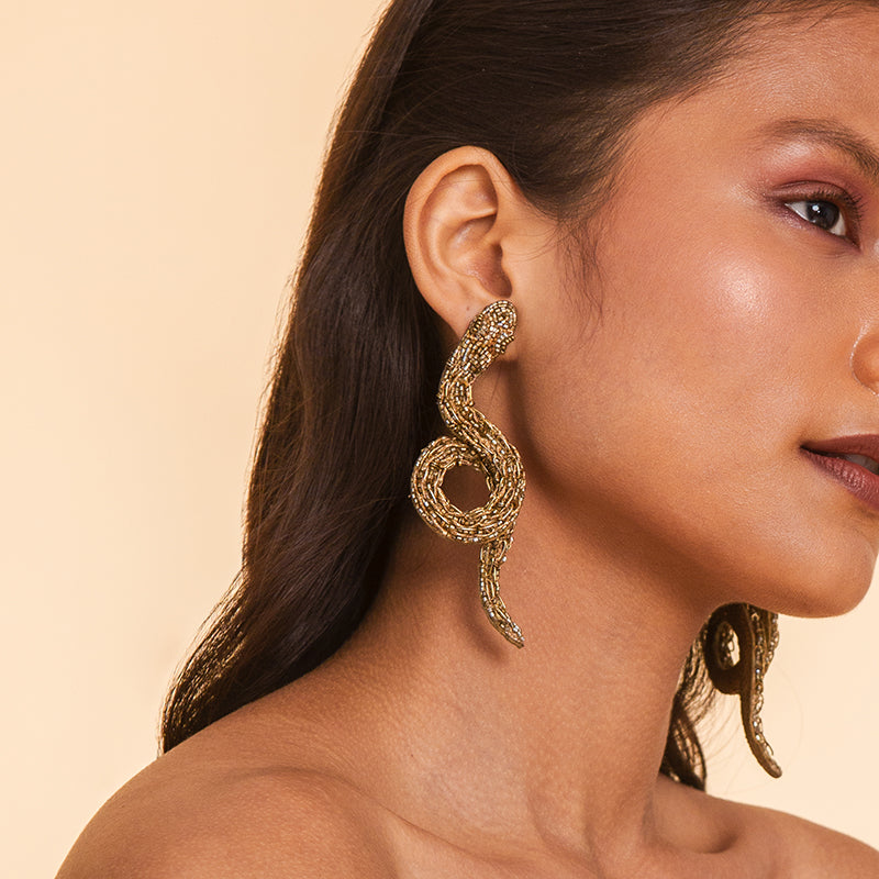 Detail of Model wearing Deepa Gurnani handmade the Boa earrings in gold color