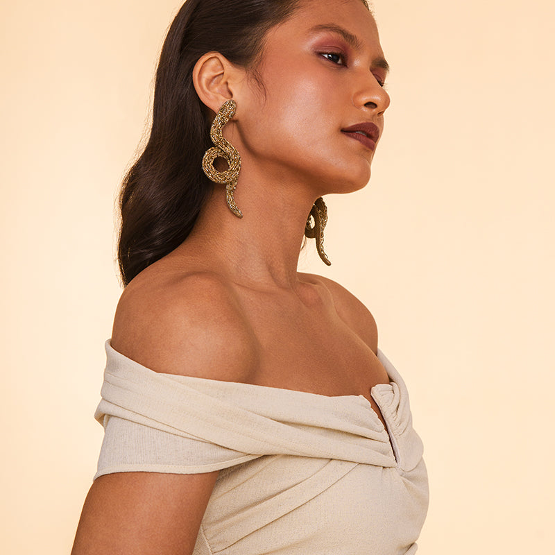 Detail of Model wearing Deepa Gurnani handmade the Boa earrings in gold color