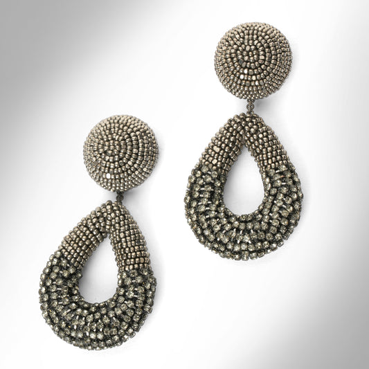 A pair of large statement dangle earrings made from gunmetal beads and chainstone, featuring a round stud top and a teardrop-shaped drop, shown on a light gray gradient background.