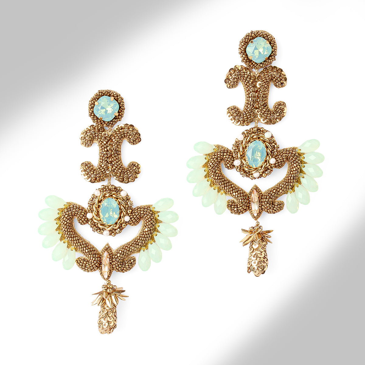 A pair of ornate gold-tone statement earrings with intricate beaded scrollwork and gold stone accents, displayed on a light gray background.