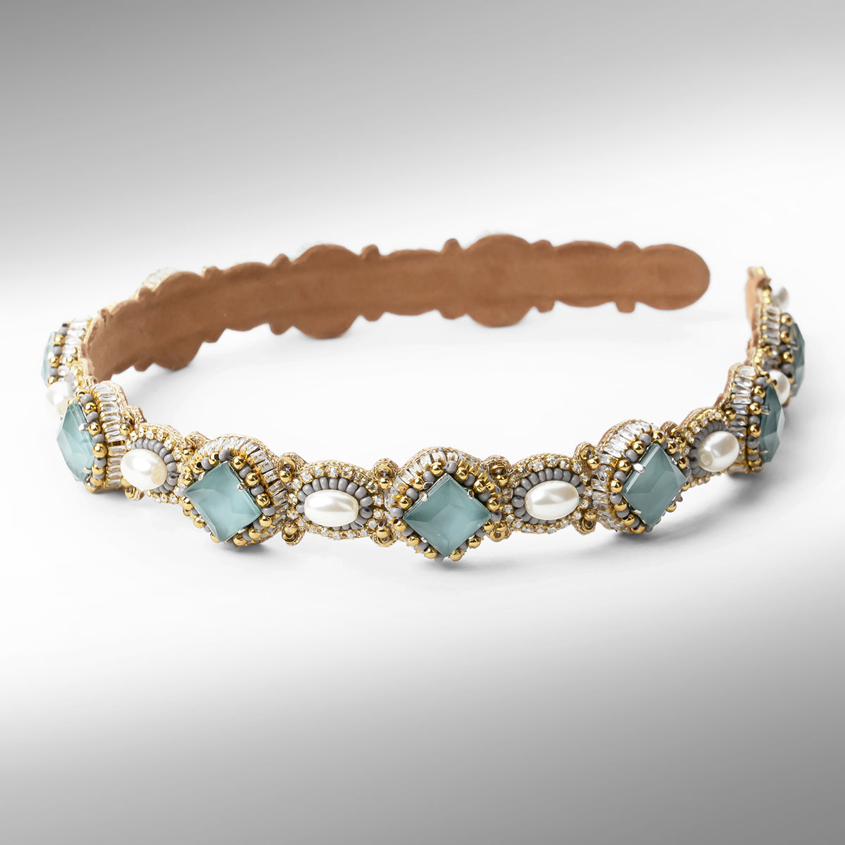  A beaded headband with scalloped edges, featuring grey stones, white faux pearls, and gold and silver beads on a neutral gray background.