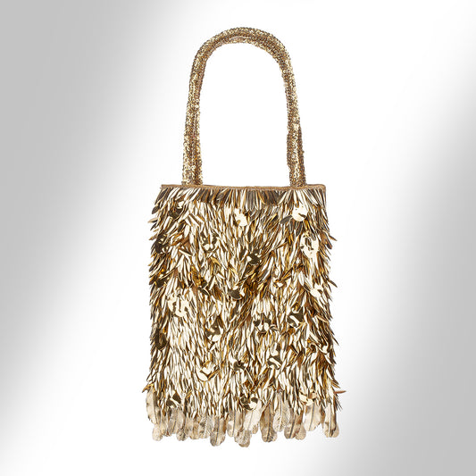 A gold metallic fringe handbag  photographed against a light gray gradient background.