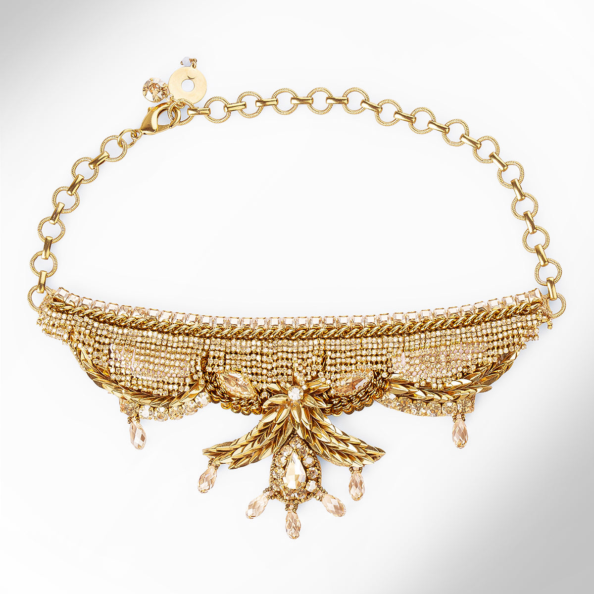 A gold-tone collar necklace featuring a wide, textured beaded band with champagne stones, and a delicate chain extender clasp, shown on a light gray background.