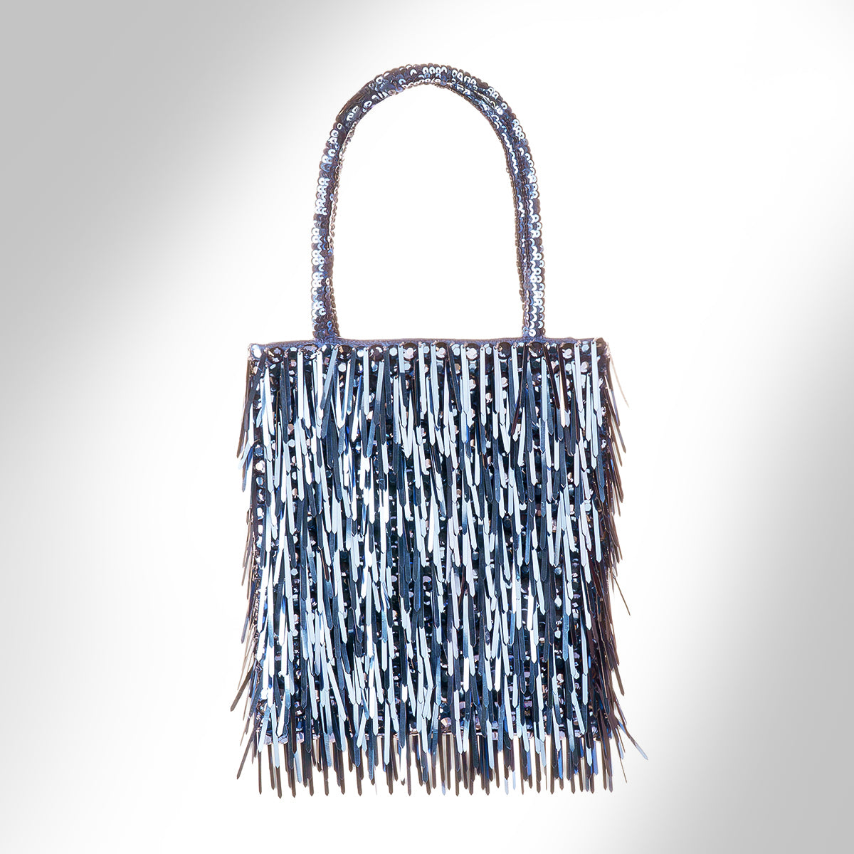 A blue metallic fringe handbag, photographed against a light gray gradient background.
