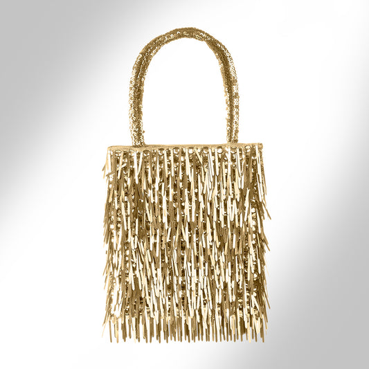 A gold metallic fringe handbag, photographed against a light gray gradient background.